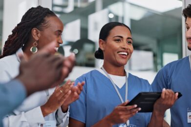 Group of healthcare workers in uniform standing together, looking happy